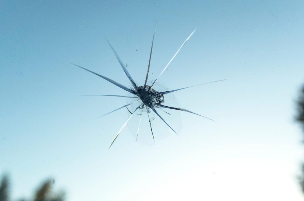Auto windshield interior looking out glass chip rock repair needed sky Close-up of rock chip damage awaiting windshield repair